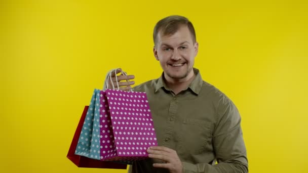 Uomo felice che mostra la parola di vendita iscrizione dalle borse della spesa, sorridente soddisfatto dei prezzi bassi — Video Stock