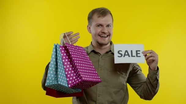 Gelukkig man tonen Sale woord inscriptie, glimlachen, op zoek naar tevreden met lage prijzen. Langzame beweging — Stockvideo