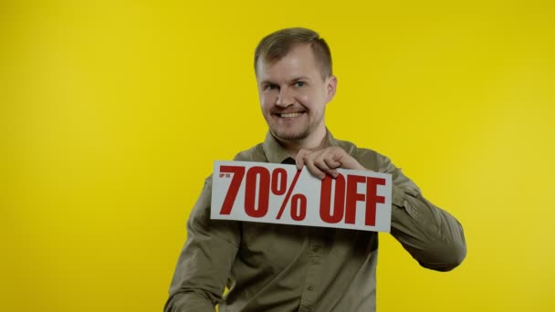 Homem mostrando até 70 por cento Off inscrição e sacos de compras, olhando satisfeito com preços baixos — Vídeo de Stock