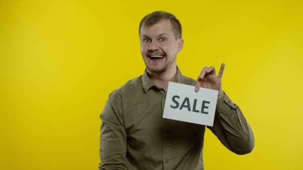 Gelukkig man tonen Sale woord inscriptie, glimlachen, op zoek naar tevreden met lage prijzen. Langzame beweging — Stockvideo