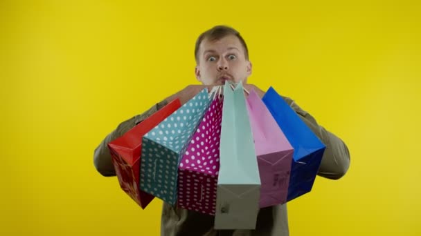 Hombre mostrando la inscripción Viernes Negro en bolsas de compras, sonriendo, satisfecho con las compras a precios bajos — Vídeos de Stock