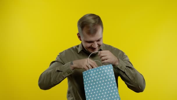 Mężczyzna pokazuje napis Black Friday z torby na zakupy, uśmiechnięty, radujące rabaty, niskie ceny — Wideo stockowe