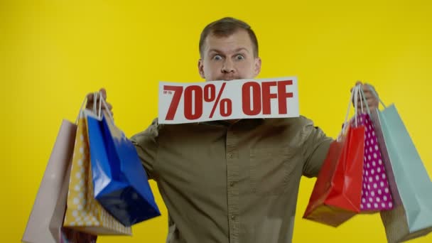 ショッピングバッグを見せて驚いた男と彼の口の中で碑文を最大70%オフ。ブラック・フライデー — ストック動画