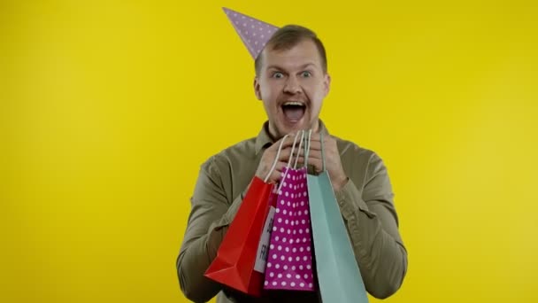 Uomo sorridente che mostra iscrizione Venerdì nero sulle borse della spesa, festeggiando, gioendo buoni sconti — Video Stock