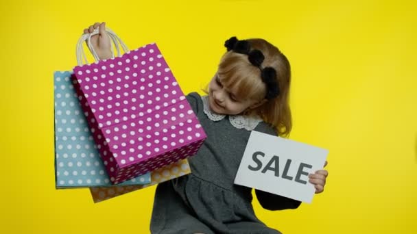 Χαριτωμένο χαρούμενο κορίτσι με πουκάμισο που δείχνει λέξη πώληση διαφήμιση πανό και τσάντες ψώνια — Αρχείο Βίντεο