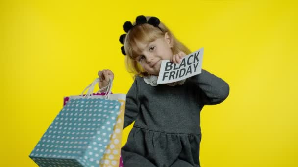 Παιδί κορίτσι με τσάντες ψώνια δείχνει Black Friday επιγραφή, ικανοποιημένος με τις χαμηλές τιμές εκπτώσεις — Αρχείο Βίντεο