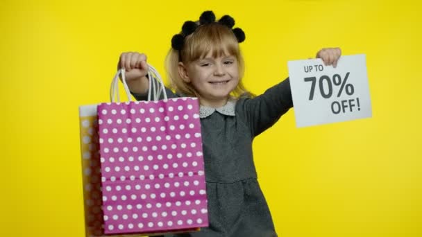 Enfant fille montrant jusqu'à 70 pour cent Hors inscription signe et sacs à provisions. Jeune élève souriant — Video