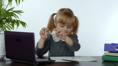Anaokulu öğrencisi kız mesafesi evde internetten öğreniyor. Çocuk dijital dizüstü bilgisayar kullanarak çalışıyor