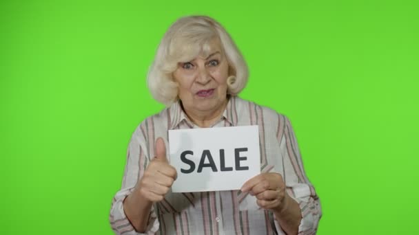 Grootmoeder tonen Sale woord inscriptie nota, tevreden met lage prijzen, winkelen op Black Friday — Stockvideo
