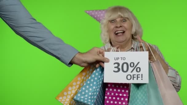 Werbung Bis zu 30 Prozent Rabatt erscheint neben der Großmutter. Frau tanzt mit Einkaufstüten — Stockvideo