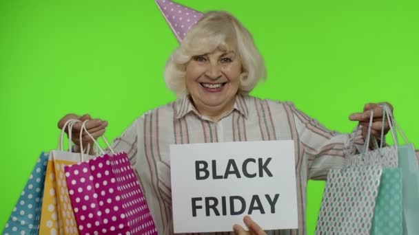 Επιγραφή διαφήμιση Black Friday εμφανίζεται δίπλα στην χαρούμενη γιαγιά με τσάντες ψώνια — Αρχείο Βίντεο