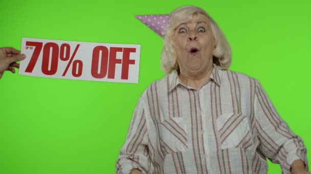 Advertentie Up To 70 Procent Off verschijnt naast oma. Vrouw viert feest met boodschappentassen — Stockvideo