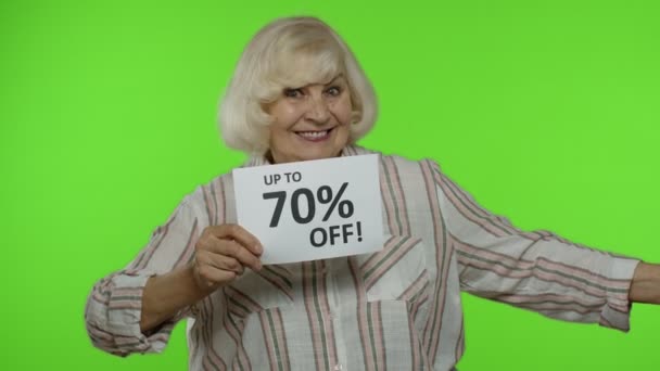 Бабушка показывает Черная пятница и до 70 процентов скидки на покупку рекламы — стоковое видео