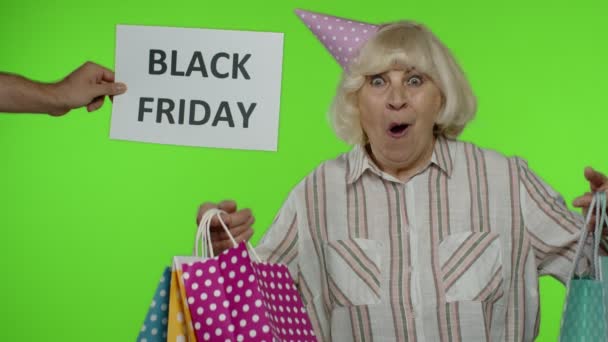 Надпись на рекламе Черная пятница появляется рядом с радостной бабушкой с пакетами — стоковое видео