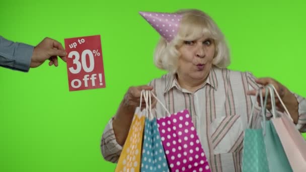 Inscrição Até 30% Off aparece ao lado da avó. Mulher comemorando com sacos de compras — Vídeo de Stock