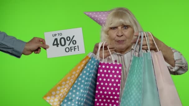 Η εγγραφή μέχρι 40% έκπτωση εμφανίζεται δίπλα στη γιαγιά. Γυναίκα γιορτάζει με τσάντες ψώνια — Αρχείο Βίντεο