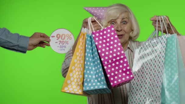 Пожилая женщина с сумками празднует, танцует, довольна низкой ценой, скидкой — стоковое видео