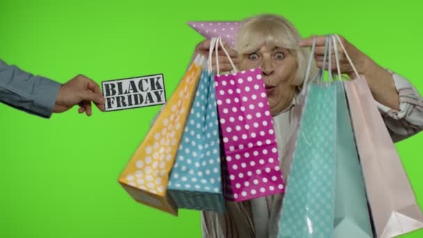 Anúncio inscrição Black Friday aparece ao lado da avó alegre com sacos de compras — Vídeo de Stock