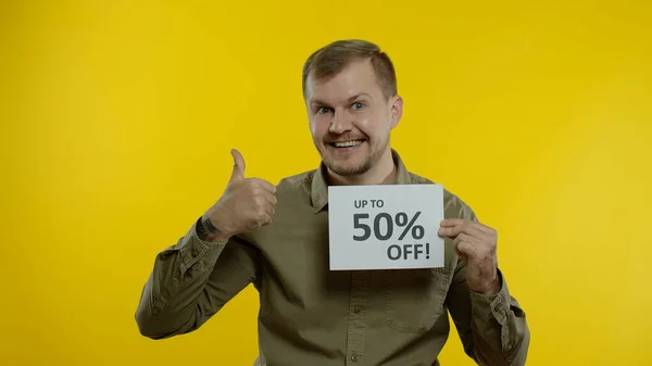 Homme souriant montrant jusqu'à 50 pour cent Off inscriptions signes, se réjouissant de bons rabais, prix bas — Photo