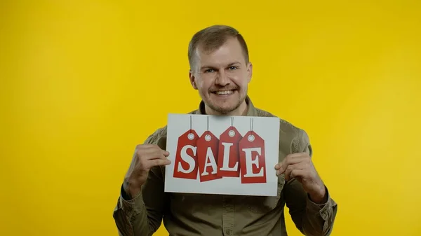Skvělé slevy. Šťastný veselý blondýny muž v modré košili ukazuje prodej slovo inzerát nápis — Stock fotografie