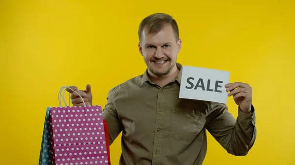 Gelukkig man tonen Sale woord inscriptie, glimlachen, op zoek naar tevreden met lage prijzen. Langzame beweging — Stockfoto