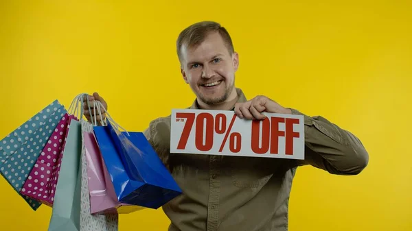 Homme montrant jusqu'à 70 pour cent Off inscription et sacs à provisions, l'air satisfait avec des prix bas — Photo