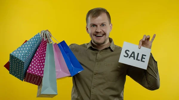 Gelukkig lachende man met boodschappentassen met zwarte vrijdag inscriptie op tassen en Sale word note — Stockfoto