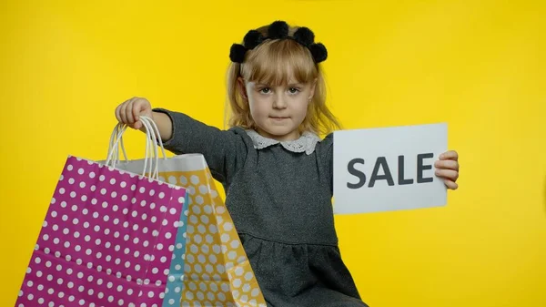 Enfant fille avec des sacs à provisions montrant Vente mot note d'inscription, souriant, se réjouissant de bonnes réductions — Photo