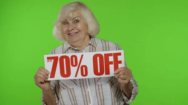 Senior Großmutter zeigt bis zu 50 Prozent Rabatt auf Anmeldung, Werbung Rabatte, schaut erstaunt — Stockfoto