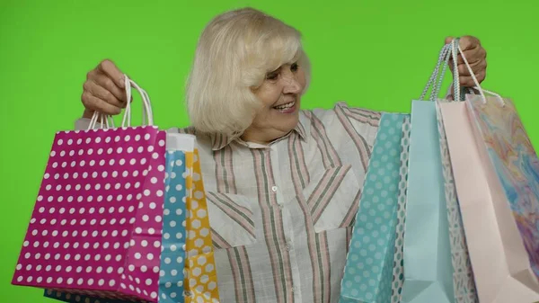 Großmutter hält Einkaufstüten in der Hand, freut sich über Rabatte im Laden, genießt den Einkauf mit niedrigen Preisen — Stockfoto
