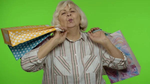 Senior Großmutter hebt Einkaufstüten, feiert, zufrieden mit dem Kauf, Rabatt. Chroma-Schlüssel — Stockfoto
