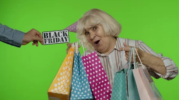 Inscripción del anuncio Viernes Negro aparece junto a la alegre abuela con bolsas de compras — Foto de Stock