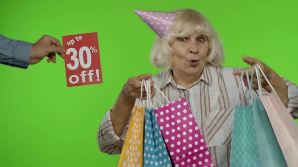 Bis zu 30 Prozent Rabatt gibt es neben der Großmutter. Frau feiert mit Einkaufstüten — Stockfoto