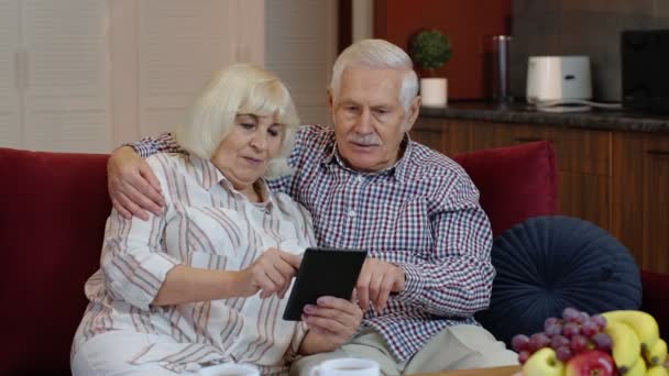 Ancianos abuelos de la vieja pareja hablando y usando tableta digital en casa. Compras por Internet — Vídeo de stock