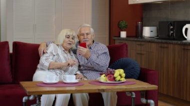 Büyükannem ve büyükbabam evdeki cep telefonlarından video görüşmesi yapıyorlar. Gülümseyen yaşlı çift