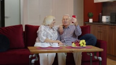 Büyükannem ve büyükbabam evdeki cep telefonlarından video görüşmesi yapıyorlar. Gülümseyen yaşlı çift