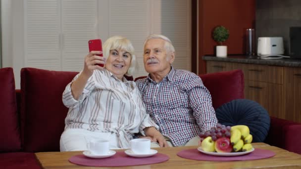 Familia mayor divirtiéndose, haciendo fotos selfies, grabando video juntos en el teléfono inteligente en casa — Vídeos de Stock