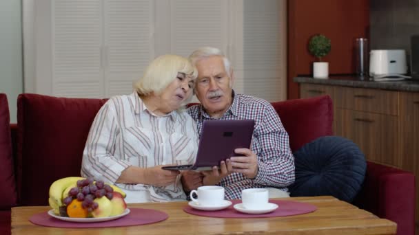 Les grands-parents aînés parlent et utilisent un ordinateur portable numérique à la maison. Verrouillage du coronavirus — Video