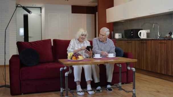 Starší prarodiče si doma povídají a používají digitální tablet. Uzamčení koronaviru — Stock video