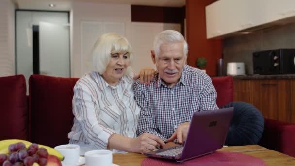 Oudere grootouders koppelen praten en het gebruik van digitale laptop computer thuis. Afsluiting van het coronavirus — Stockvideo