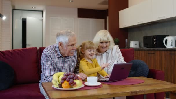 Idősebb kaukázusi pár gyermek lány unokája használja a laptop, vicces videók nézése — Stock videók