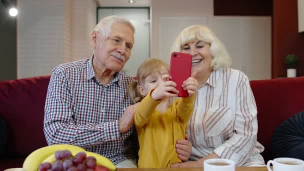 Senior pareja abuelos con niño nieta haciendo selfie fotos juntos en el teléfono móvil — Vídeo de stock