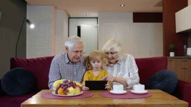 Старшая белая пара с милой девочкой внучка с помощью планшета, смотреть смешные видео — стоковое видео