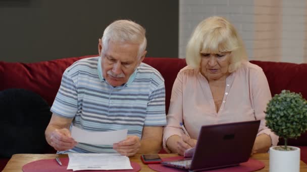 Senior couple checking counting bills bank loan payment doing paperwork discuss unpaid debt taxes — Stock video