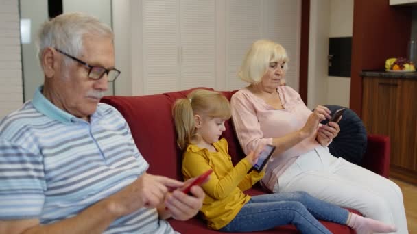 Abuelos de pareja mayor con nieta niña usando tableta digital, teléfono móvil — Vídeos de Stock