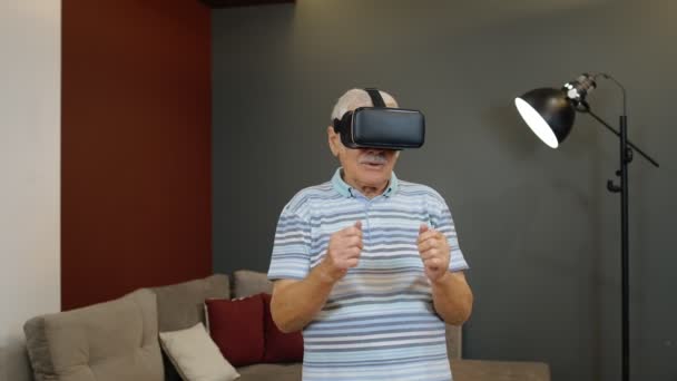 Ανώτερος παππούς άνθρωπος σε εικονικά γυαλιά ακουστικά βλέποντας εκπληκτικό 3D βίντεο σε κράνος 360 VR στο σπίτι — Αρχείο Βίντεο