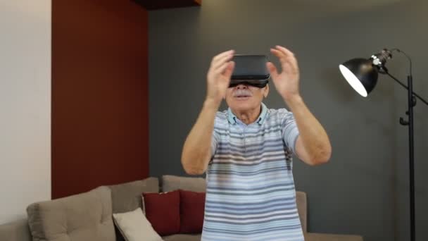 Szczęśliwy senior korzystający z okularów wirtualnej rzeczywistości, próbujący czegoś dotknąć, oglądający wideo 3D — Wideo stockowe