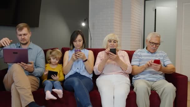 Adicta a la familia gadgets utilizando el teléfono móvil, tableta, portátil ignorándose mutuamente en casa. Obsesión — Vídeos de Stock