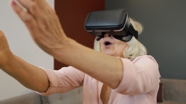 Happy senior woman in virtual reality headset glasses, trying to touch something, watching 3D video — Stock Video