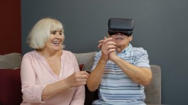 VR kulaklıklı büyükbaba ve büyükanne oyun oynuyorlar, sanal gerçeklik 3D video izliyorlar.